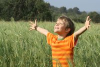 Young child in a field with arms oustretched in joy