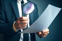 Man holding magnifying glass looking at paper